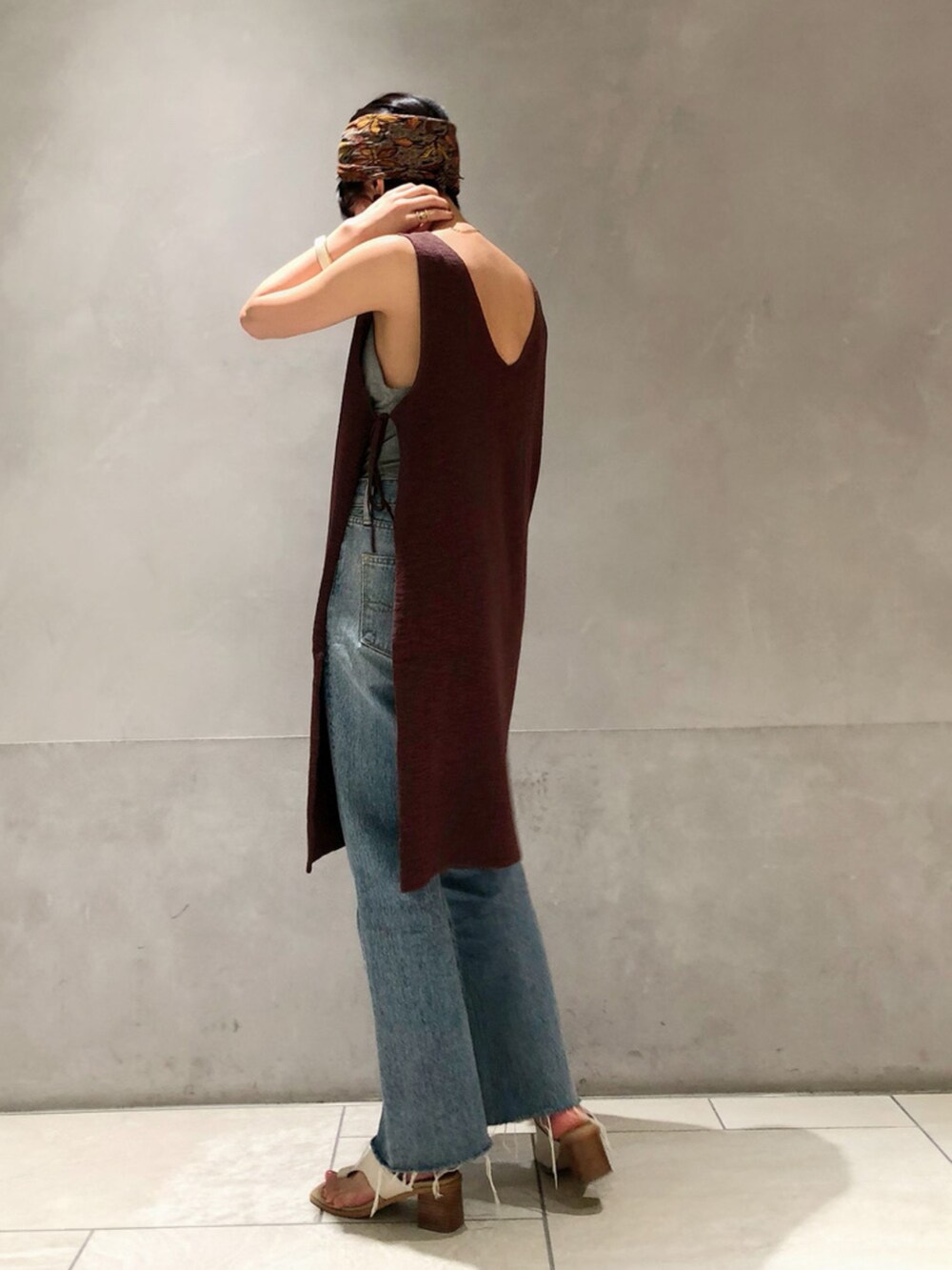 ブルー系のデニムパンツ、ブラウン系のベストを着用したレディースの春コーディネートの2枚目の写真
