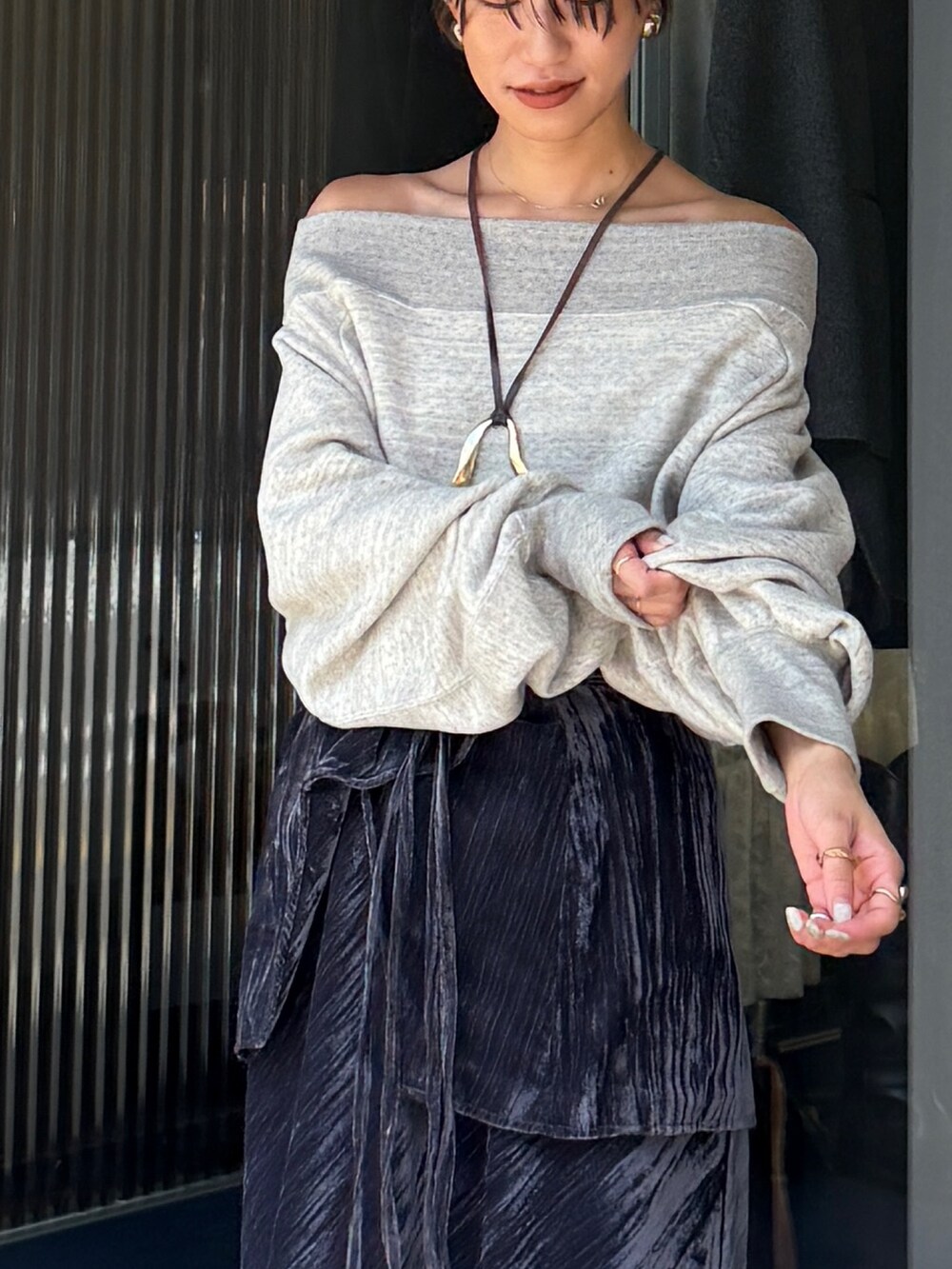 グレー系のスウェット、ブラック系のスカート、ゴールド系のネックレスを着用したレディースの夏コーディネートの3枚目の写真