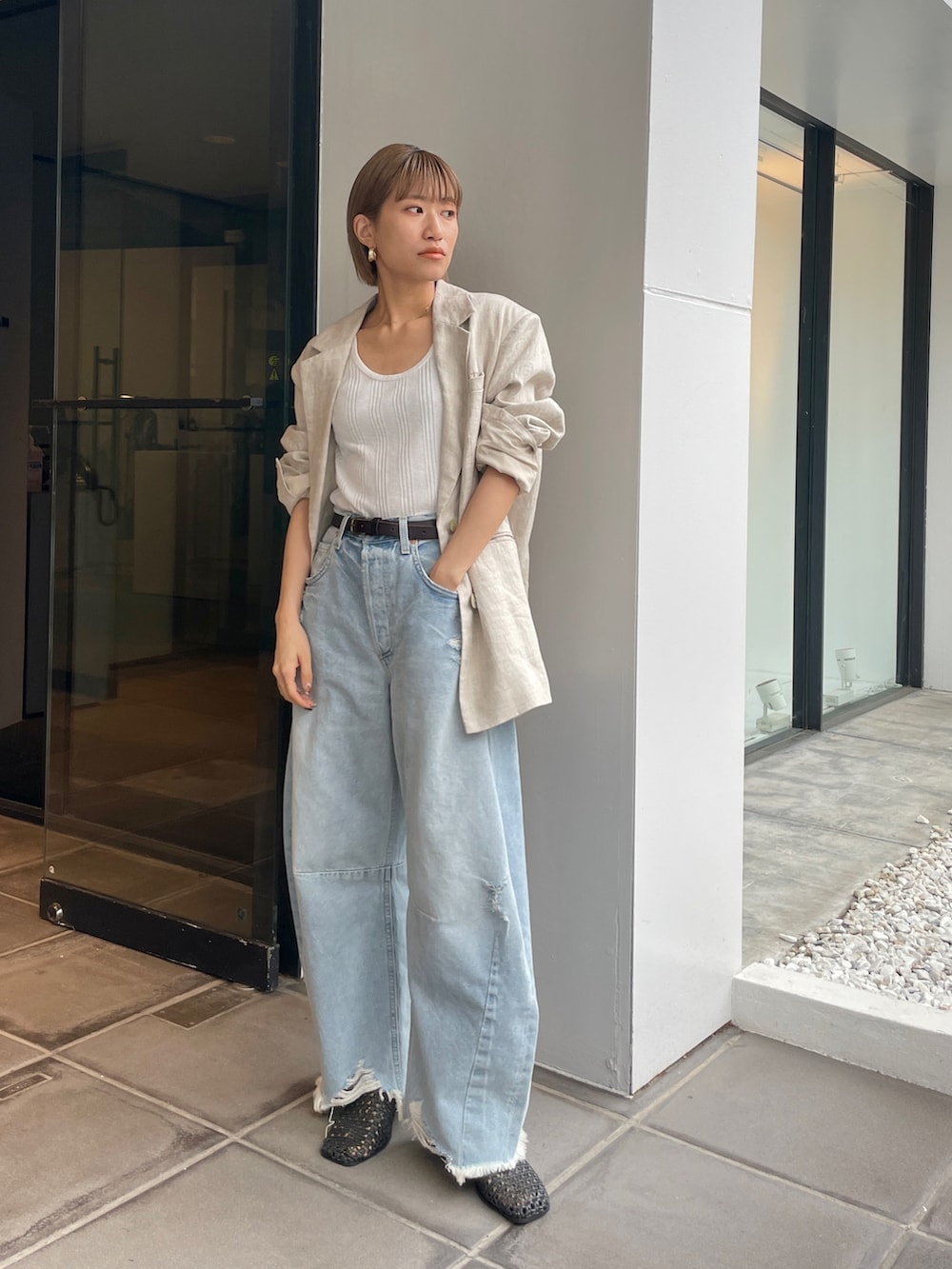 ベージュ系のテーラードジャケット、ホワイト系のタンクトップを着用したレディースの春コーディネートの3枚目の写真