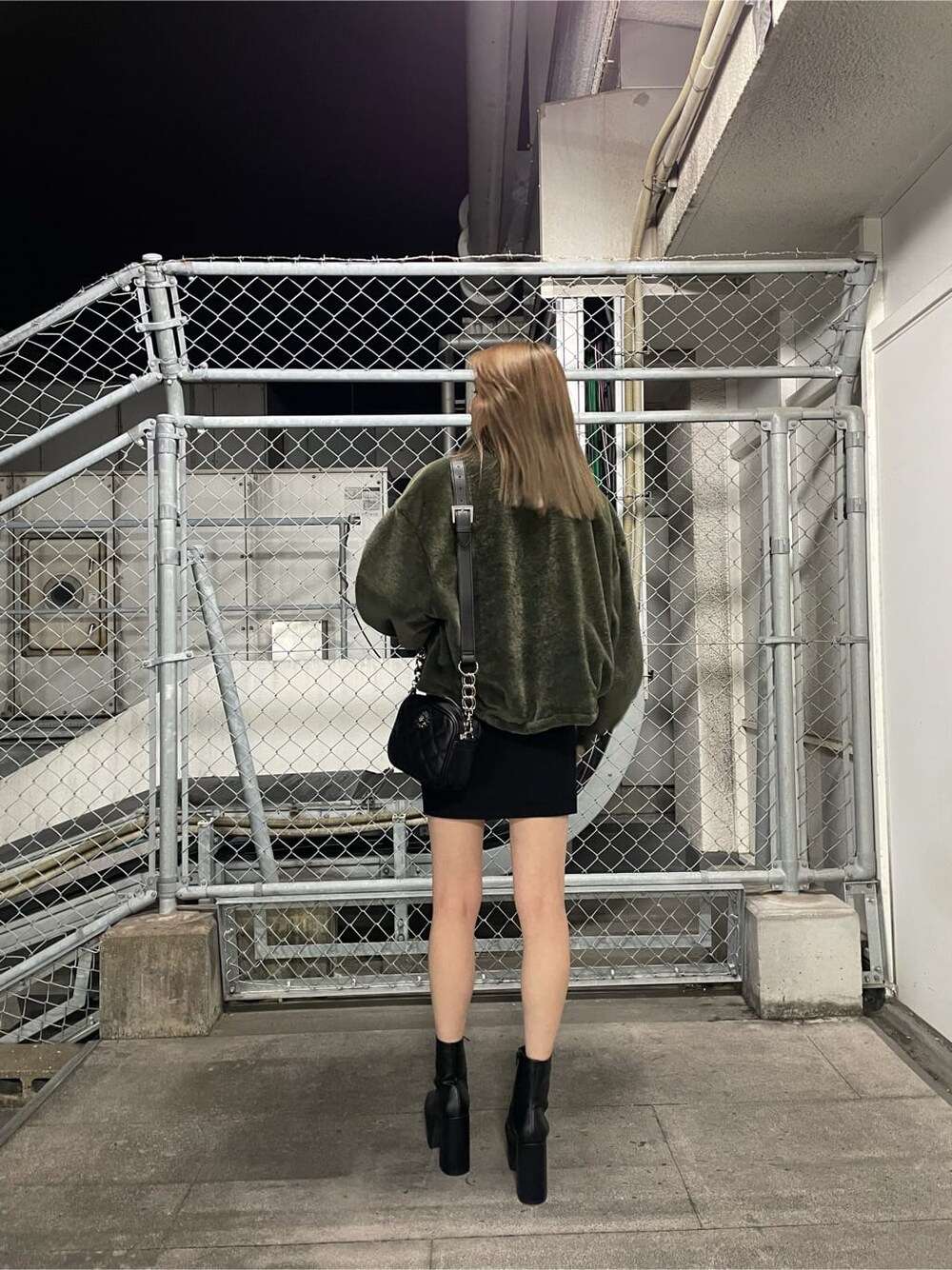 ブラック系のワンピース、ベージュ系のブルゾン、ブラック系のブーツを着用したレディースの秋コーディネートの2枚目の写真