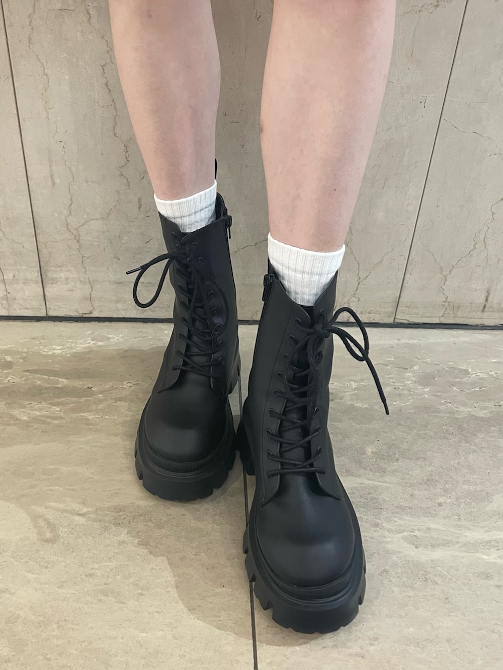 グリーン系のタンクトップ、ブラック系のスカート、ブラック系のブーツを着用したレディースの春コーディネートの7枚目の写真