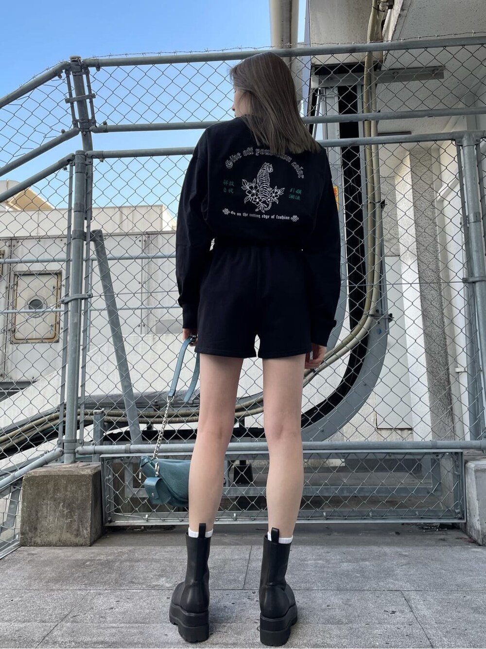 ブラック系のスウェットパンツ、ブラック系のブーツ、ブルー系のボディバッグ/ウエストポーチを着用したレディースの冬コーディネートの2枚目の写真