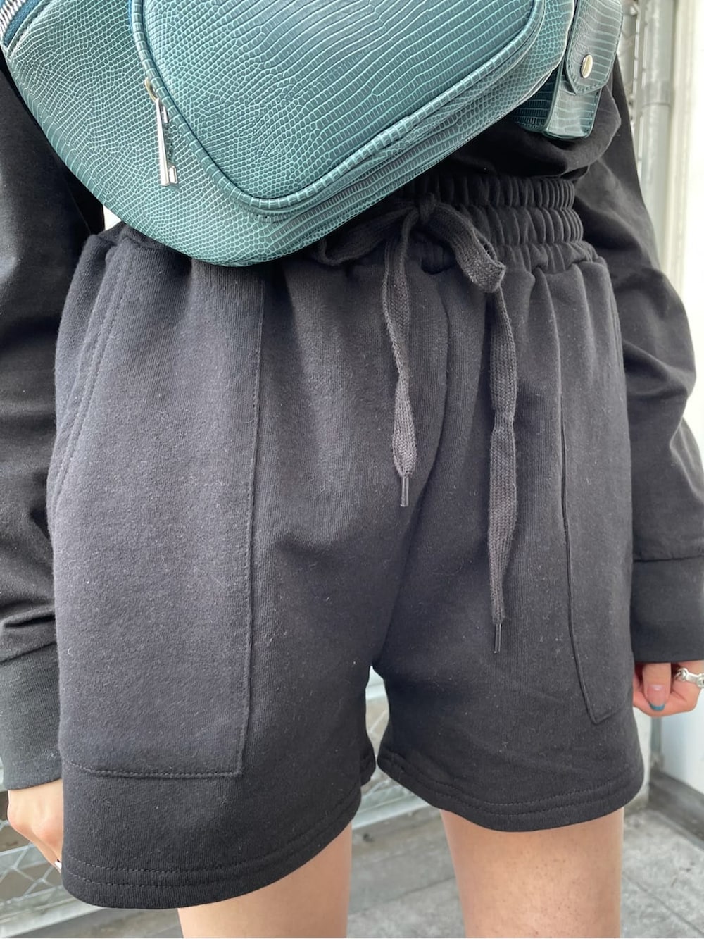 ブラック系のスウェットパンツ、ブラック系のブーツ、ブルー系のボディバッグ/ウエストポーチを着用したレディースの冬コーディネートの4枚目の写真