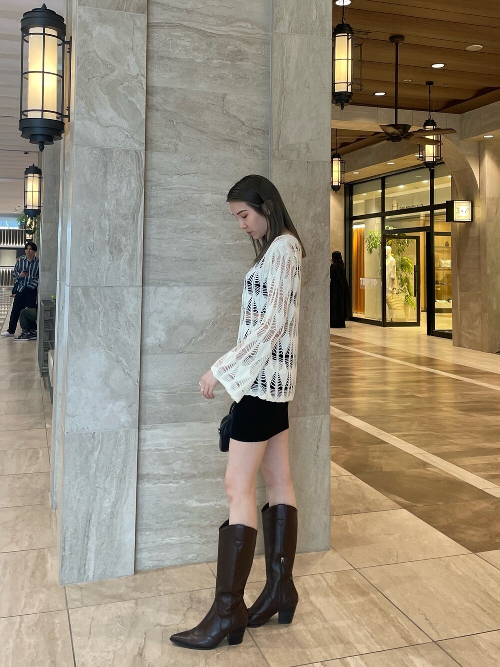 ホワイト系のカーディガン/ボレロ、ブラック系のキャミソール、ブラック系のスカートを着用したレディースの春コーディネートの2枚目の写真