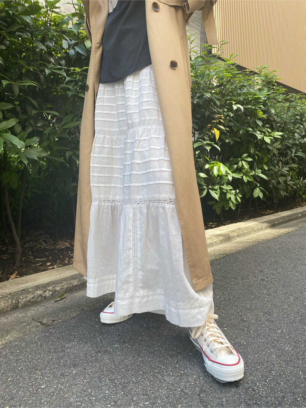 ベージュ系のトレンチコート、ホワイト系のスカート、グレー系のTシャツ/カットソーを着用したレディースの夏コーディネートの5枚目の写真