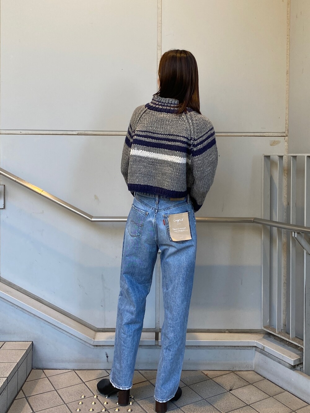 グレー系のニット/セーター、ブルー系のデニムパンツ、ブラック系のブーツを着用したレディースの秋コーディネートの3枚目の写真