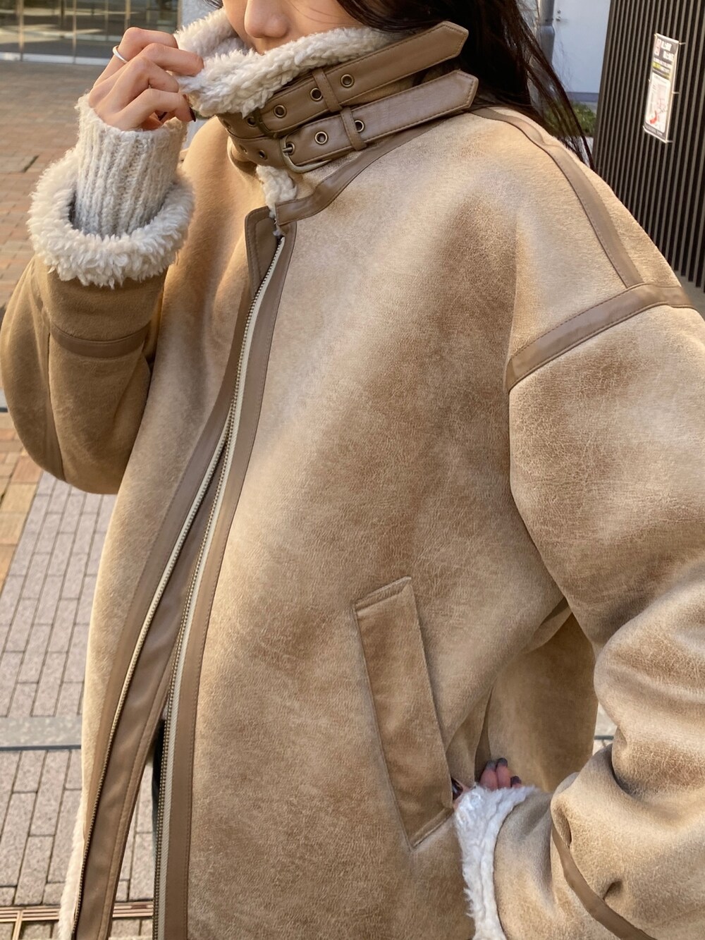 ベージュ系のムートンコート、ホワイト系のニット/セーター、ブルー系のデニムパンツを着用したレディースの冬コーディネートの5枚目の写真