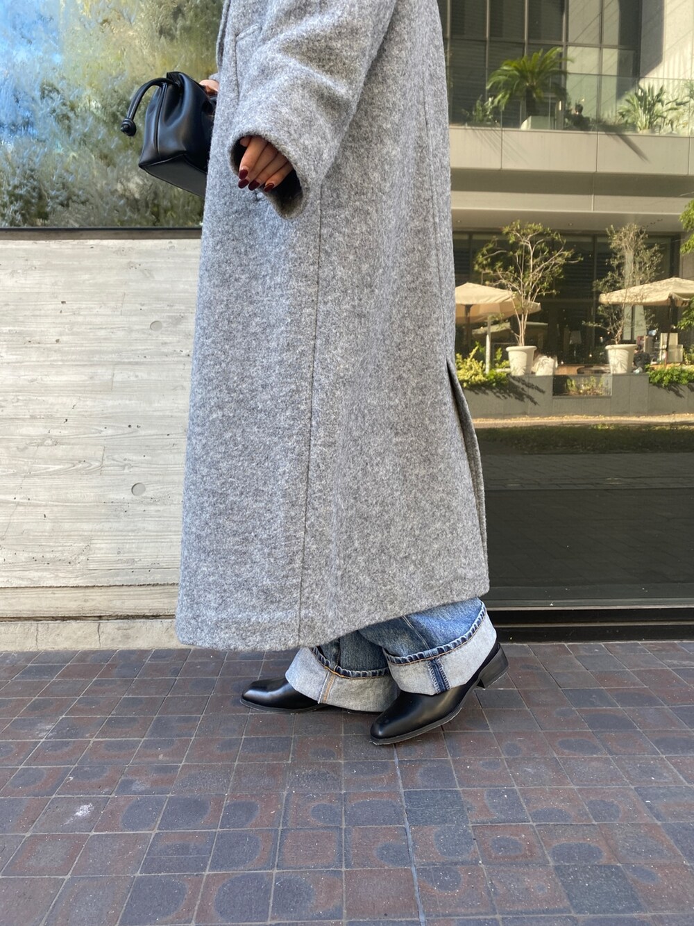 ホワイト系のニット/セーター、グレー系のチェスターコート、ブルー系のデニムパンツを着用したレディースの秋コーディネートの8枚目の写真