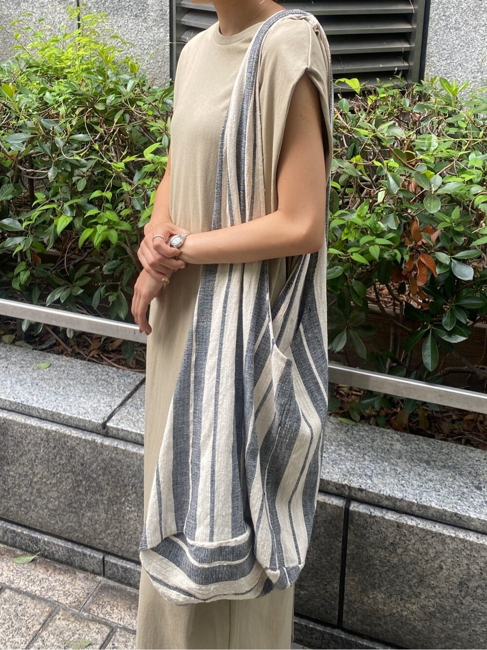 ブラック系のサンダル、ベージュ系のワンピース、ブルー系のデニムパンツを着用したレディースの夏コーディネートの6枚目の写真