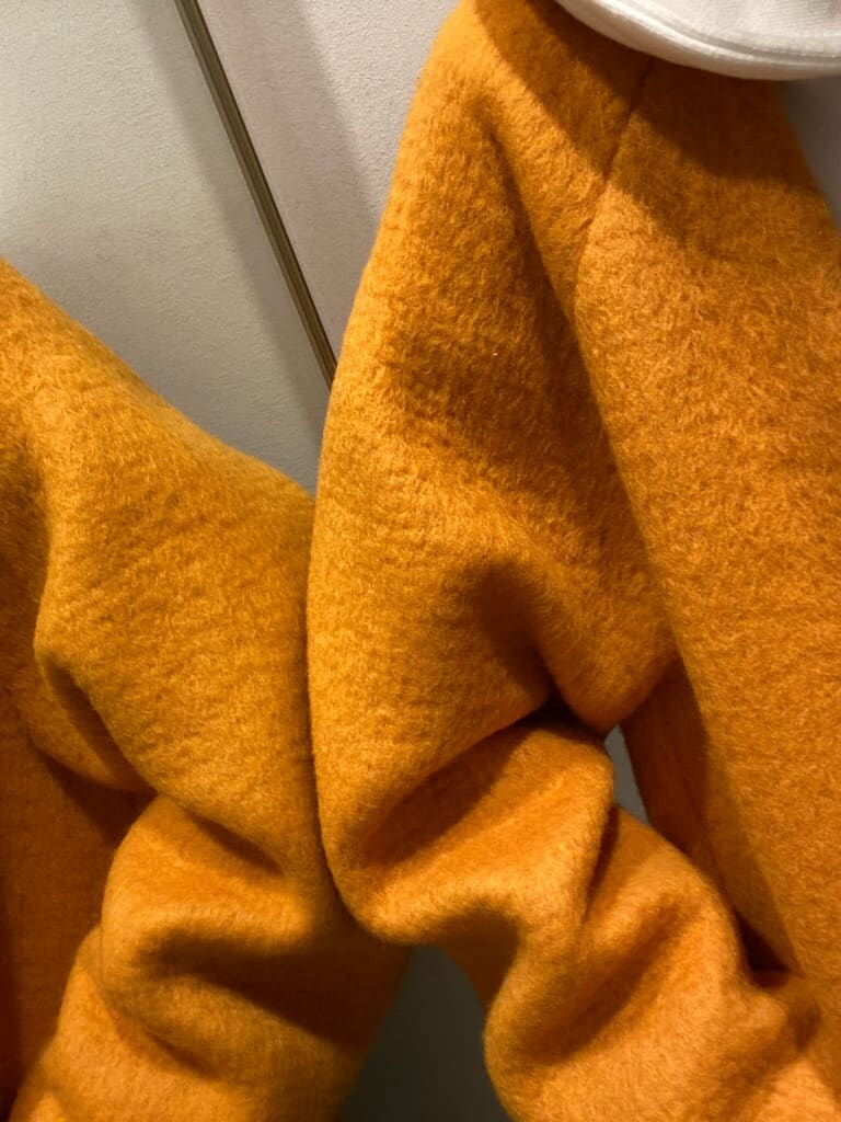 イエロー系のテーラードジャケット、ブラウン系のブーツ、ブルー系のデニムパンツを着用したレディースの秋コーディネートの7枚目の写真