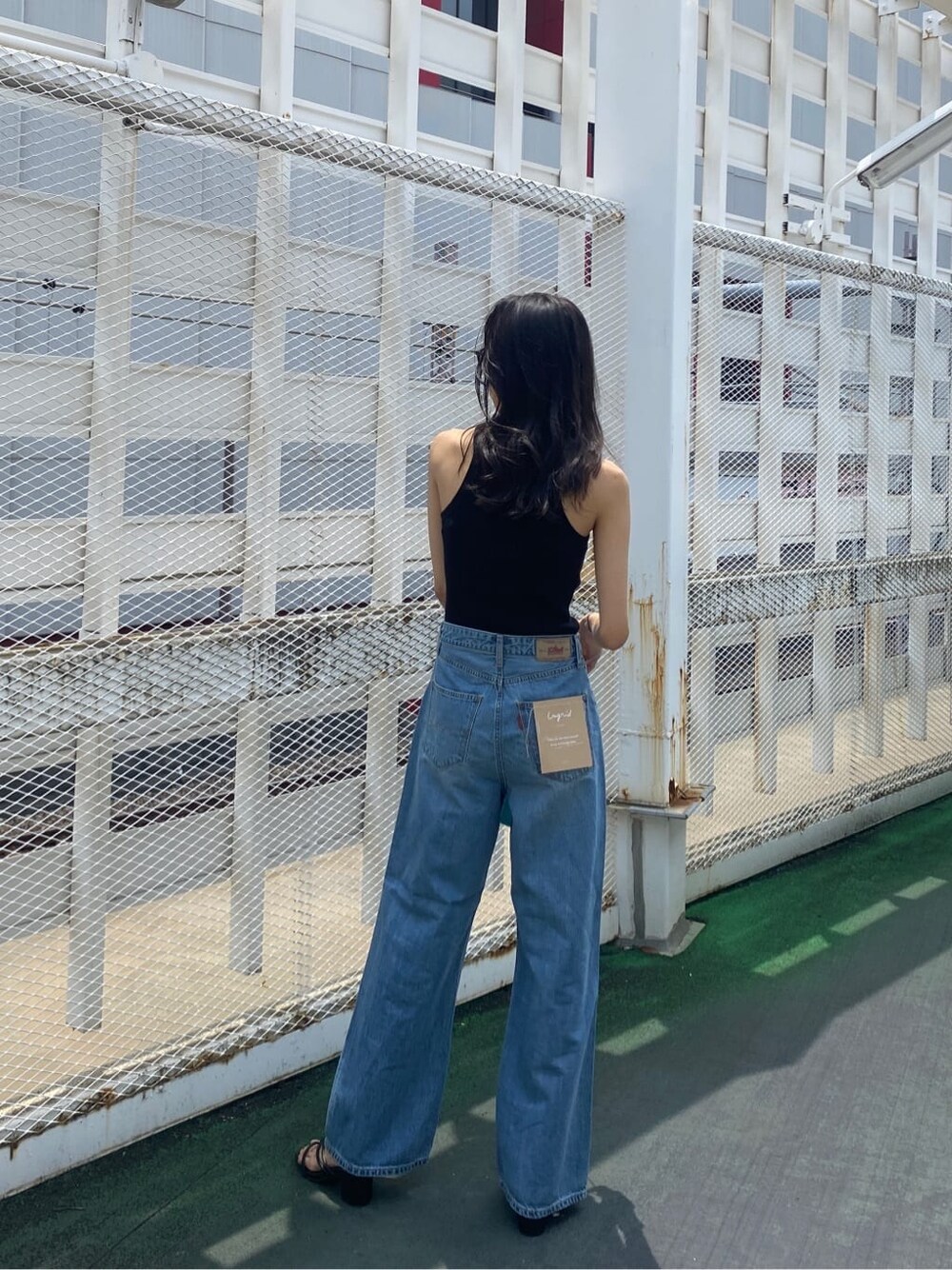 ブラック系のサンダル、ブルー系のハンドバッグ、ブラック系のタンクトップを着用したレディースの夏コーディネートの4枚目の写真