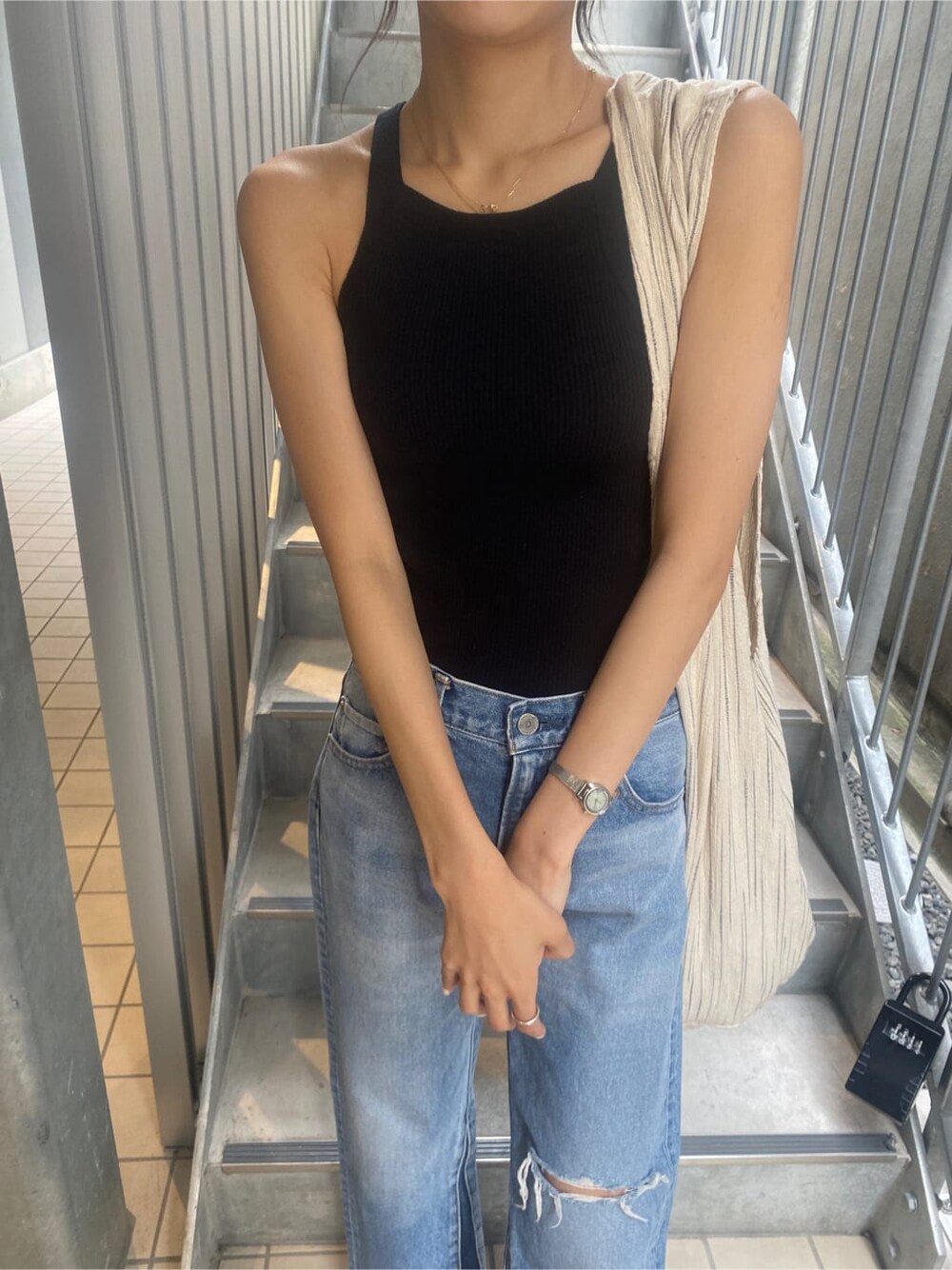 ブルー系のデニムパンツ、その他のハンドバッグ、ブラック系のタンクトップを着用したレディースの春コーディネートの5枚目の写真