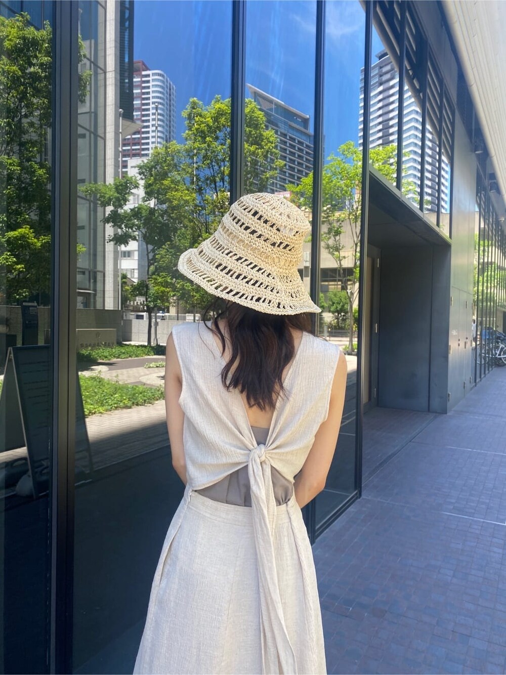 ブラック系のサンダル、ホワイト系のワンピース、ベージュ系のハットを着用したレディースの夏コーディネートの4枚目の写真