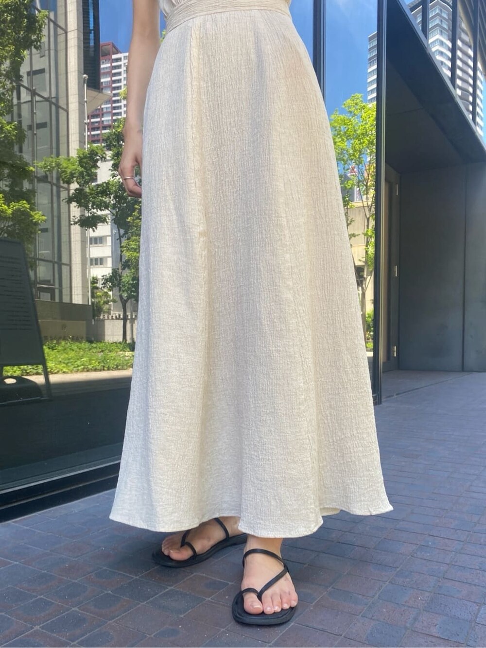 ブラック系のサンダル、ホワイト系のワンピース、ベージュ系のハットを着用したレディースの夏コーディネートの5枚目の写真