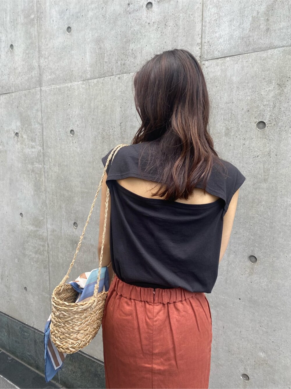 ベージュ系のかごバッグ、ブラック系のタンクトップ、オレンジ系のスカートを着用したレディースの夏コーディネートの4枚目の写真