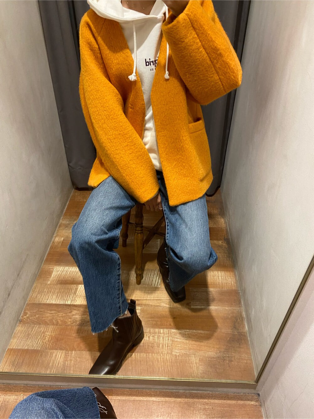 イエロー系のテーラードジャケット、ブラウン系のブーツ、ブルー系のデニムパンツを着用したレディースの秋コーディネートの3枚目の写真