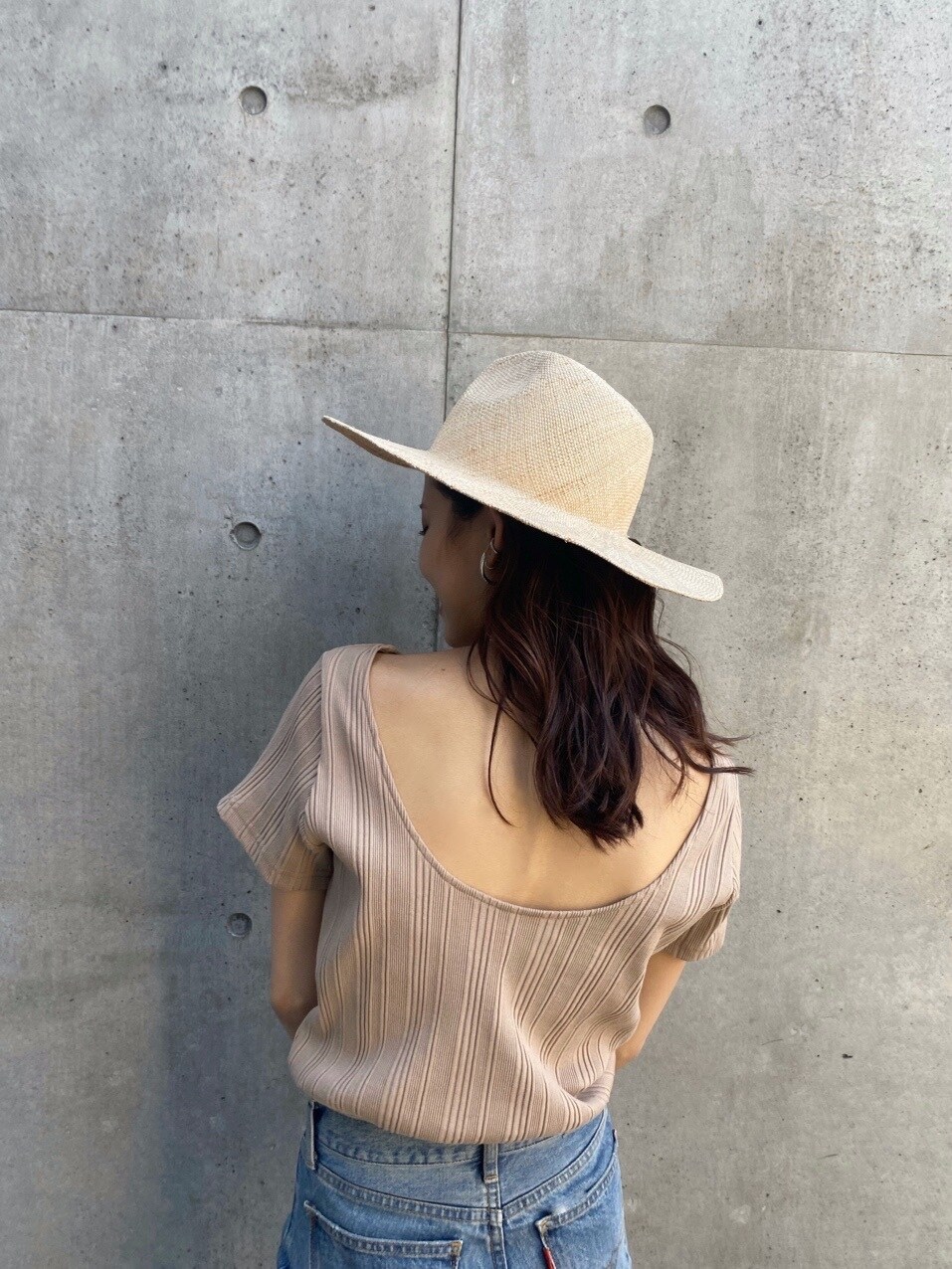 ブルー系のデニムパンツ、ベージュ系のTシャツ/カットソー、ベージュ系のハットを着用したレディースの春コーディネートの3枚目の写真