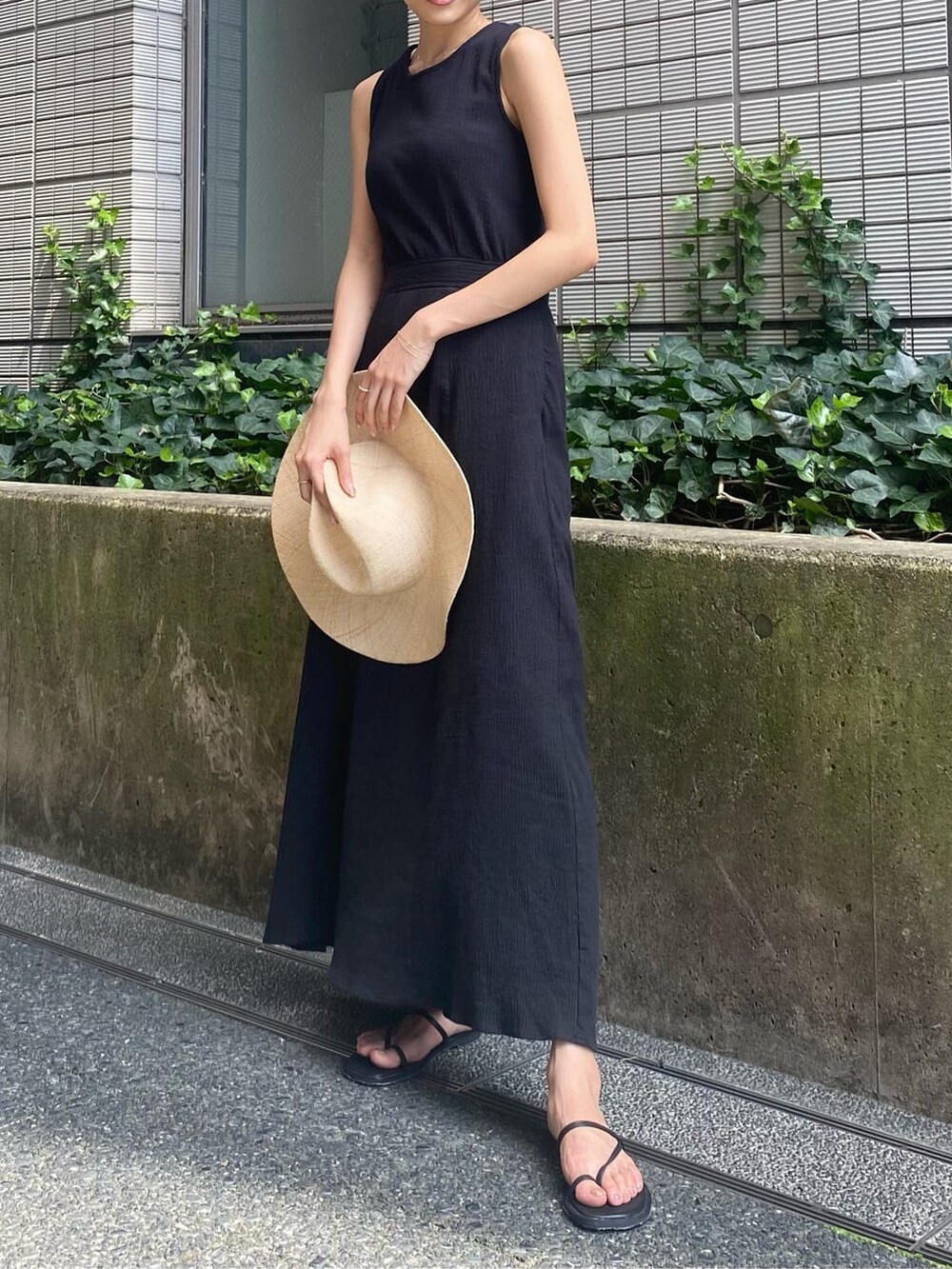 ブラック系のワンピース、ブラック系のサンダル、ホワイト系のタンクトップを着用したレディースの夏コーディネートの3枚目の写真