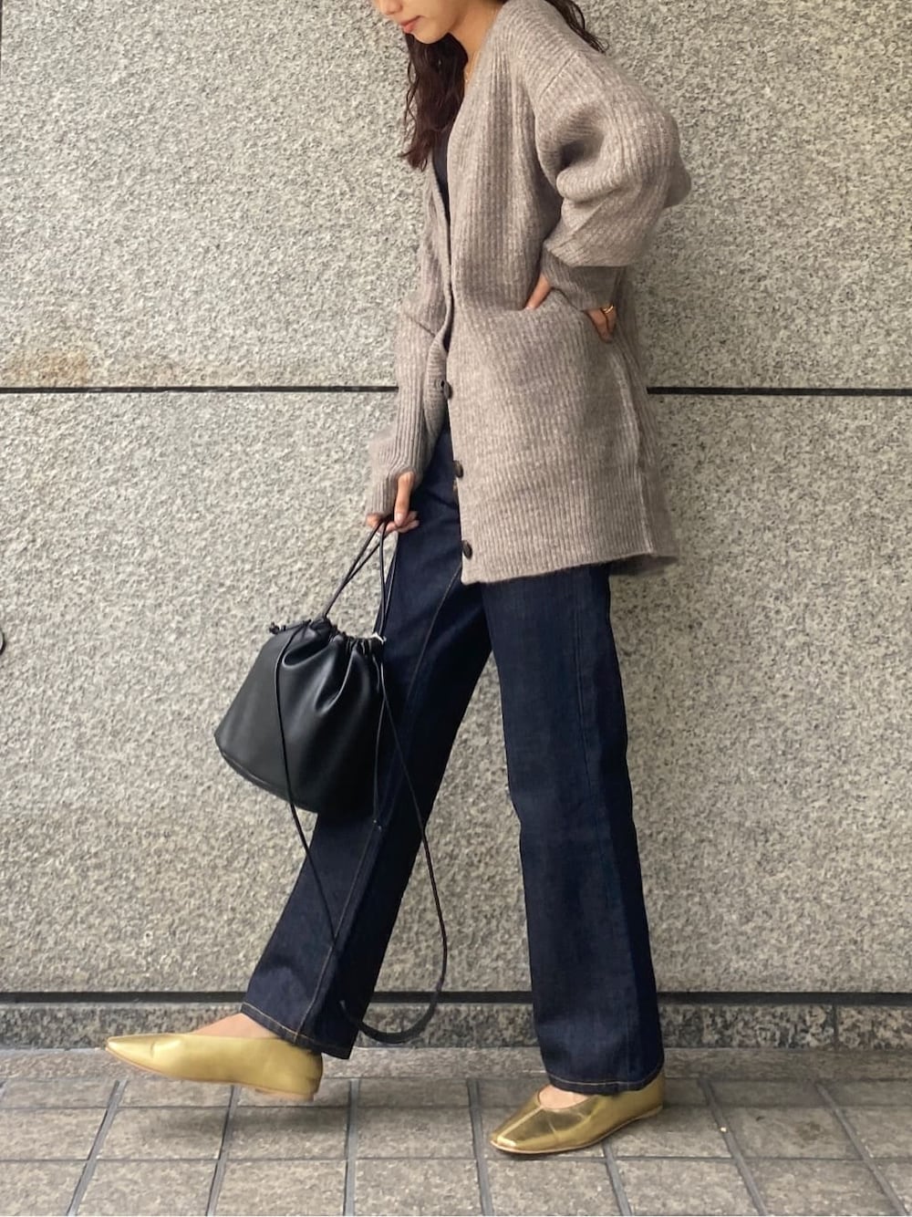 ゴールド系のパンプス、ブラック系のハンドバッグ、ブルー系のデニムパンツを着用したレディースの秋コーディネートの3枚目の写真