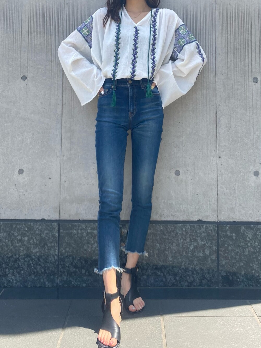 ブルー系のデニムパンツ、ホワイト系のシャツ/ブラウス、ブラック系のサンダルを着用したレディースの春コーディネートの2枚目の写真