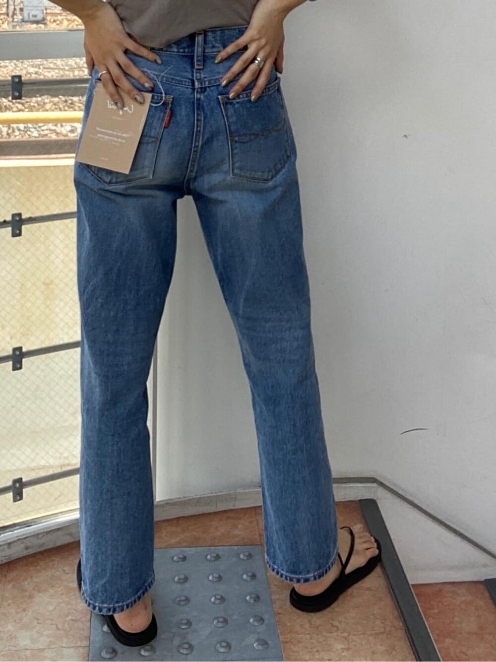 ブルー系のデニムパンツ、ブラック系のハットを着用したレディースの夏コーディネートの2枚目の写真