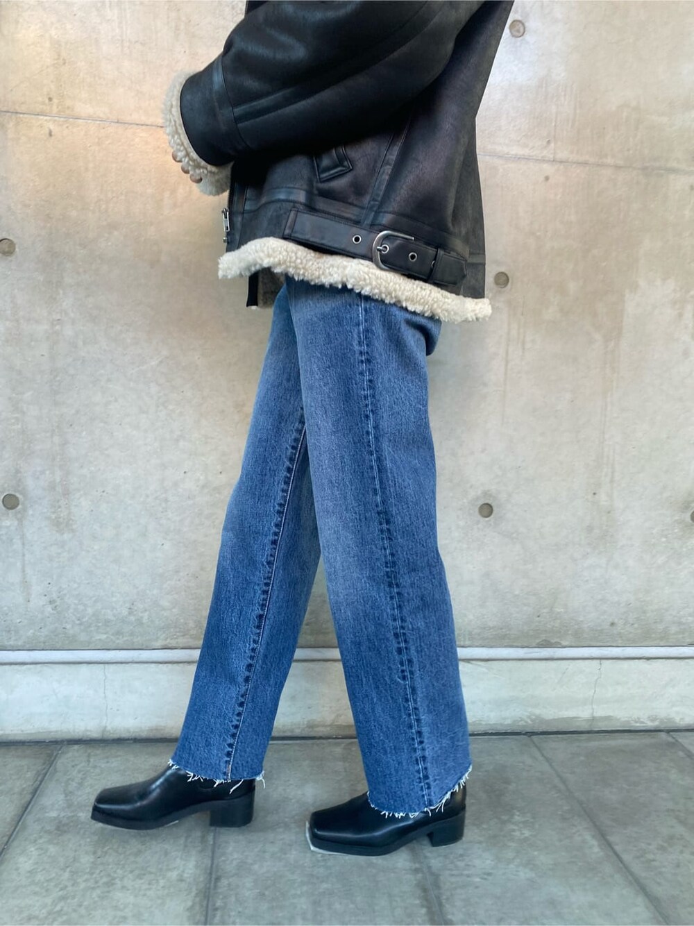 ブラック系のブルゾン、ブルー系のデニムパンツ、グレー系のニット/セーターを着用したレディースの秋コーディネートの5枚目の写真