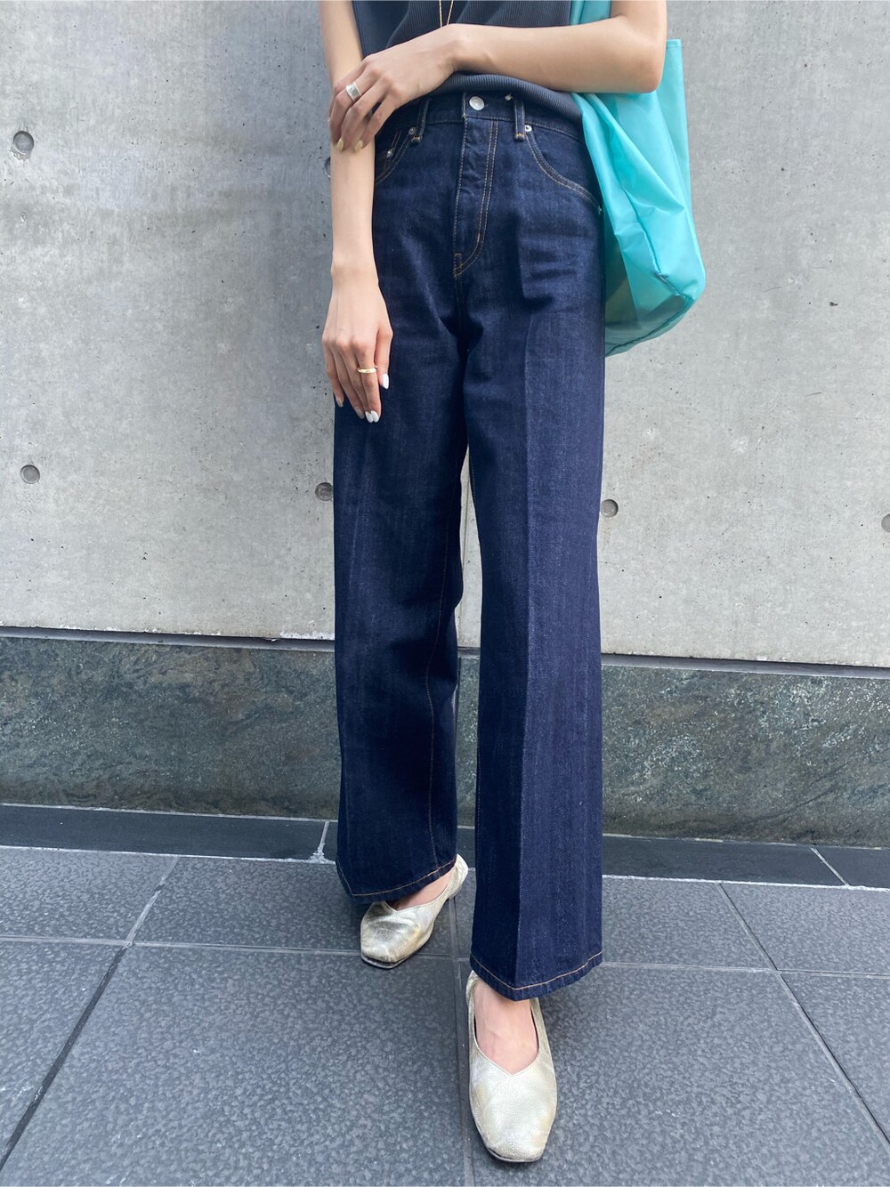 ブルー系のハンドバッグ、ブルー系のデニムパンツ、グレー系のタンクトップを着用したレディースの春コーディネートの7枚目の写真