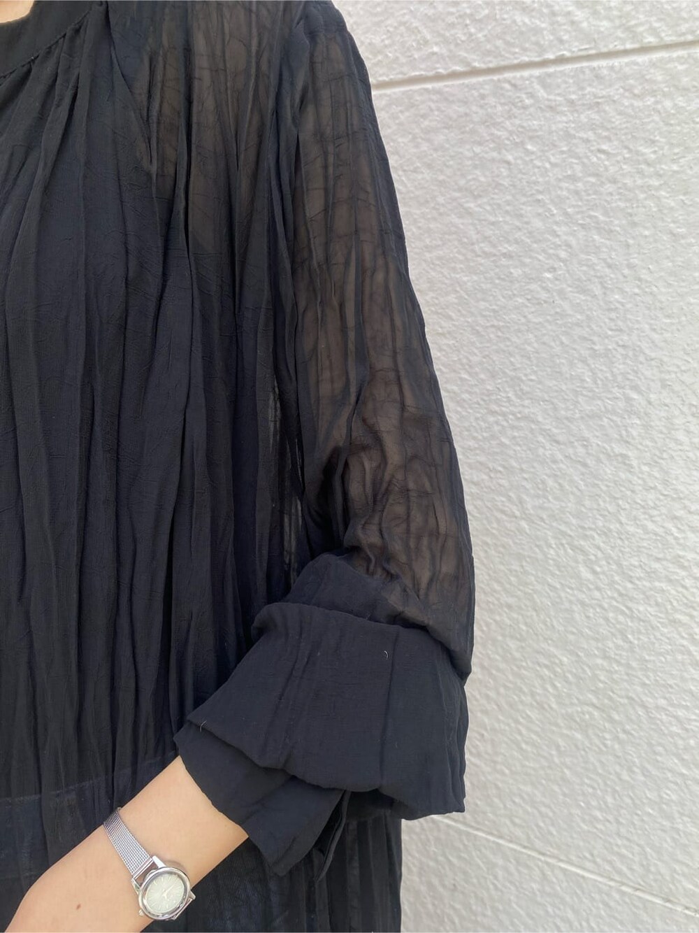 ブルー系のデニムパンツ、ブラック系のワンピース、ベージュ系のかごバッグを着用したレディースの春コーディネートの4枚目の写真