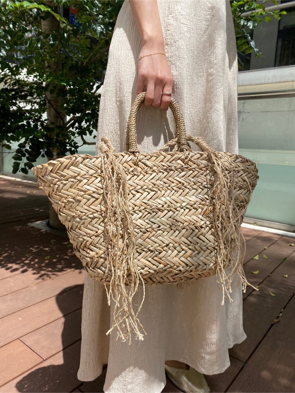 ベージュ系のかごバッグ、ホワイト系のワンピースを着用したレディースの春コーディネートの7枚目の写真