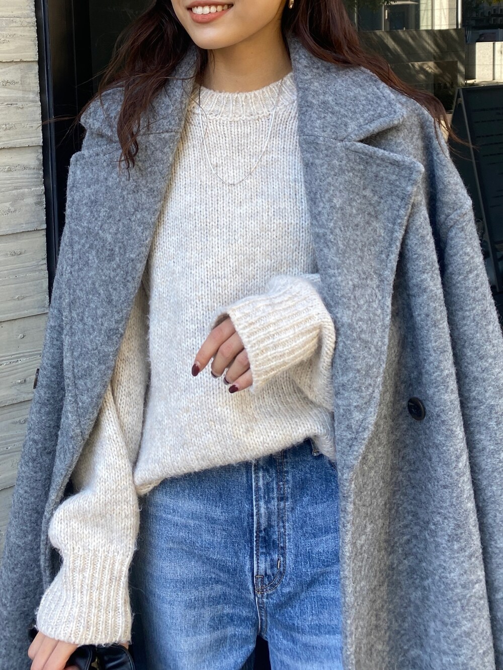 ホワイト系のニット/セーター、グレー系のチェスターコート、ブルー系のデニムパンツを着用したレディースの秋コーディネートの4枚目の写真