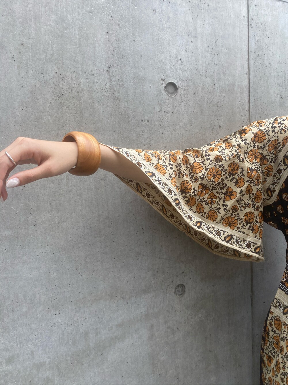 ブラウン系のサンダル、イエロー系のワンピース、ブラウン系のブレスレットを着用したレディースの夏コーディネートの5枚目の写真