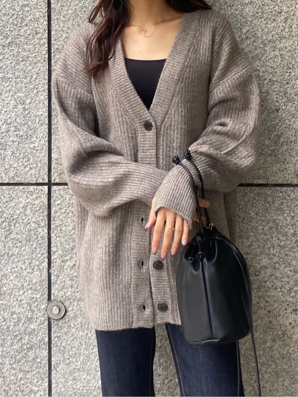 ゴールド系のパンプス、ブラック系のハンドバッグ、ブルー系のデニムパンツを着用したレディースの秋コーディネートの4枚目の写真