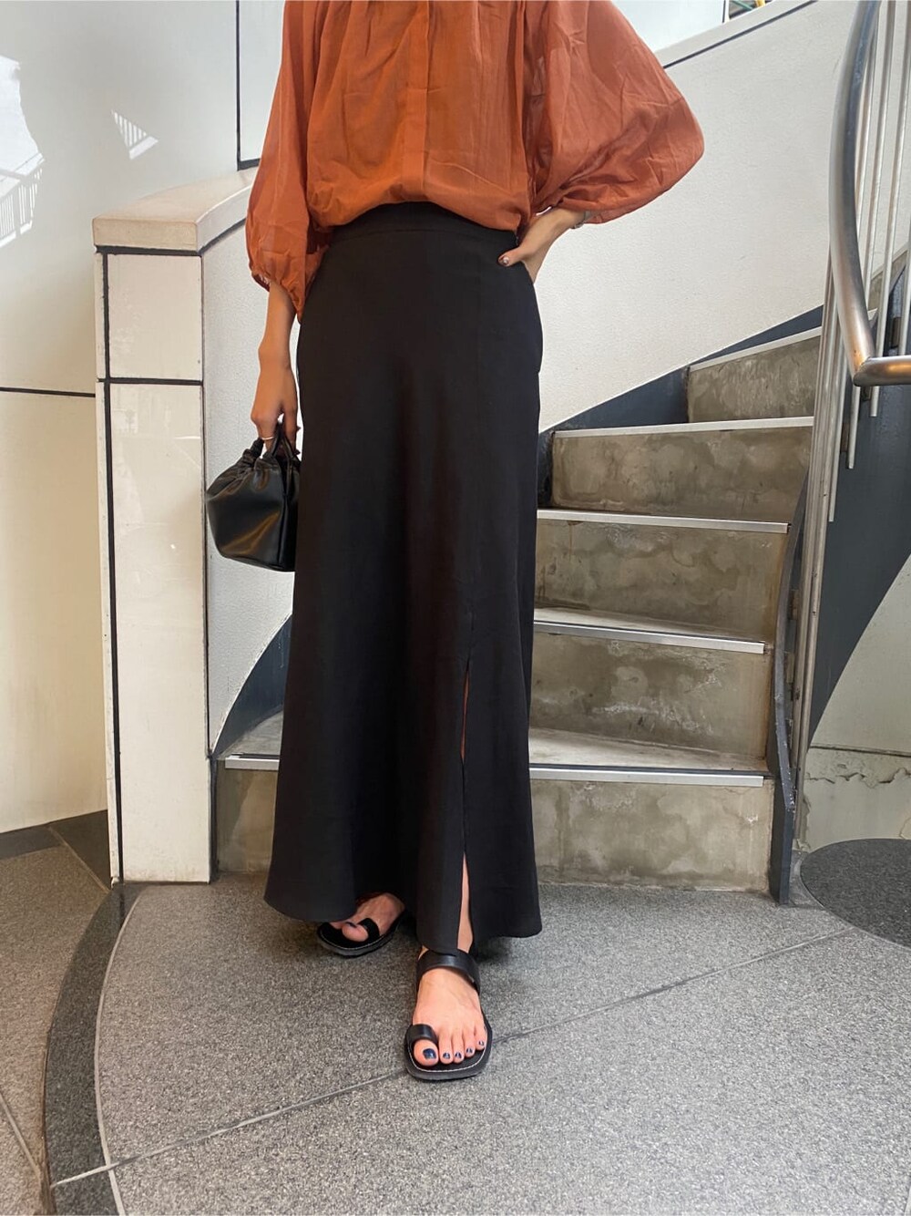 ブラック系のサンダル、オレンジ系のシャツ/ブラウス、ブラック系のスカートを着用したレディースの夏コーディネートの7枚目の写真