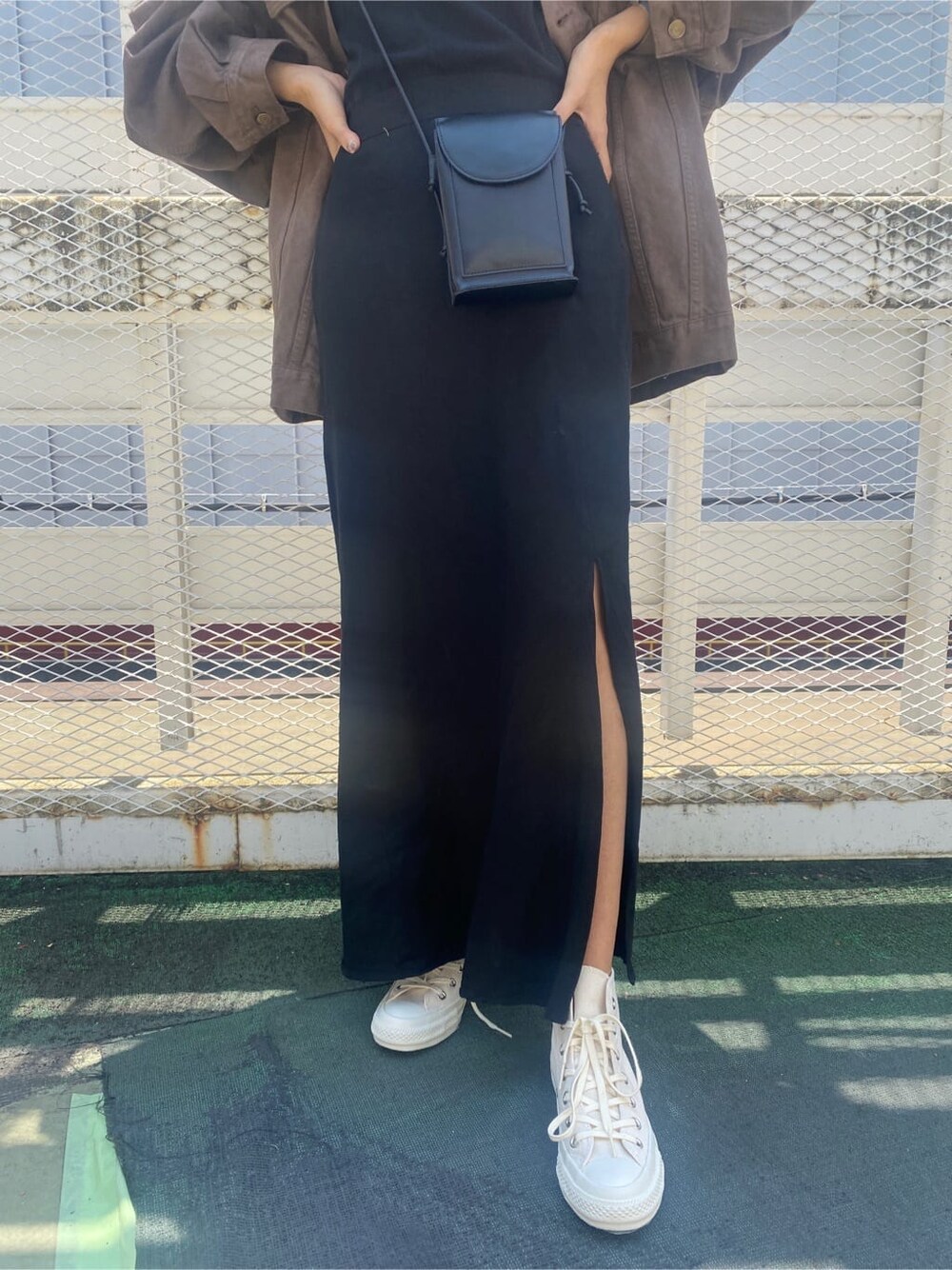 ブラウン系のデニムジャケット、ブラック系のスカート、ブラック系のキャミソールを着用したレディースの夏コーディネートの7枚目の写真