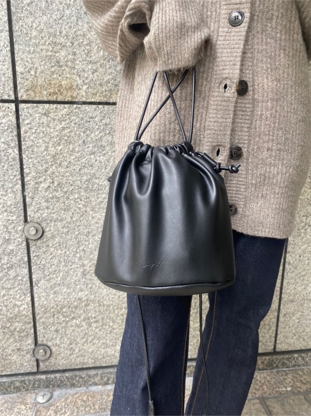 ゴールド系のパンプス、ブラック系のハンドバッグ、ブルー系のデニムパンツを着用したレディースの秋コーディネートの6枚目の写真