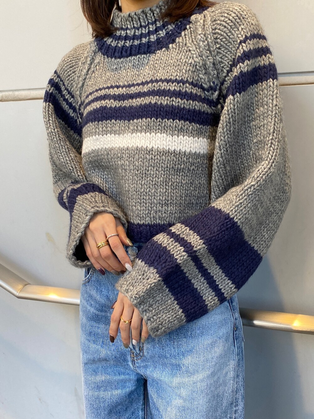 グレー系のニット/セーター、ブルー系のデニムパンツ、ブラック系のブーツを着用したレディースの秋コーディネートの4枚目の写真