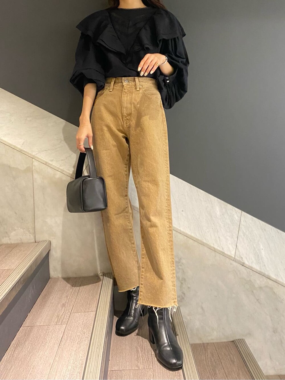 ブラック系のシャツ/ブラウス、ブラック系のハンドバッグ、ベージュ系のデニムパンツを着用したレディースの冬コーディネートの2枚目の写真