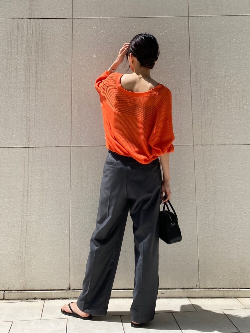 グレー系のその他パンツ、ブラック系のハンドバッグ、オレンジ系のカーディガン/ボレロを着用したレディースの春コーディネートの2枚目の写真