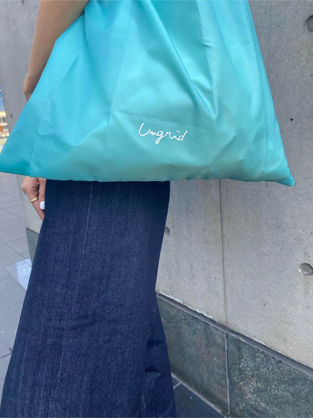 ブルー系のハンドバッグ、ブルー系のデニムパンツ、グレー系のタンクトップを着用したレディースの春コーディネートの6枚目の写真