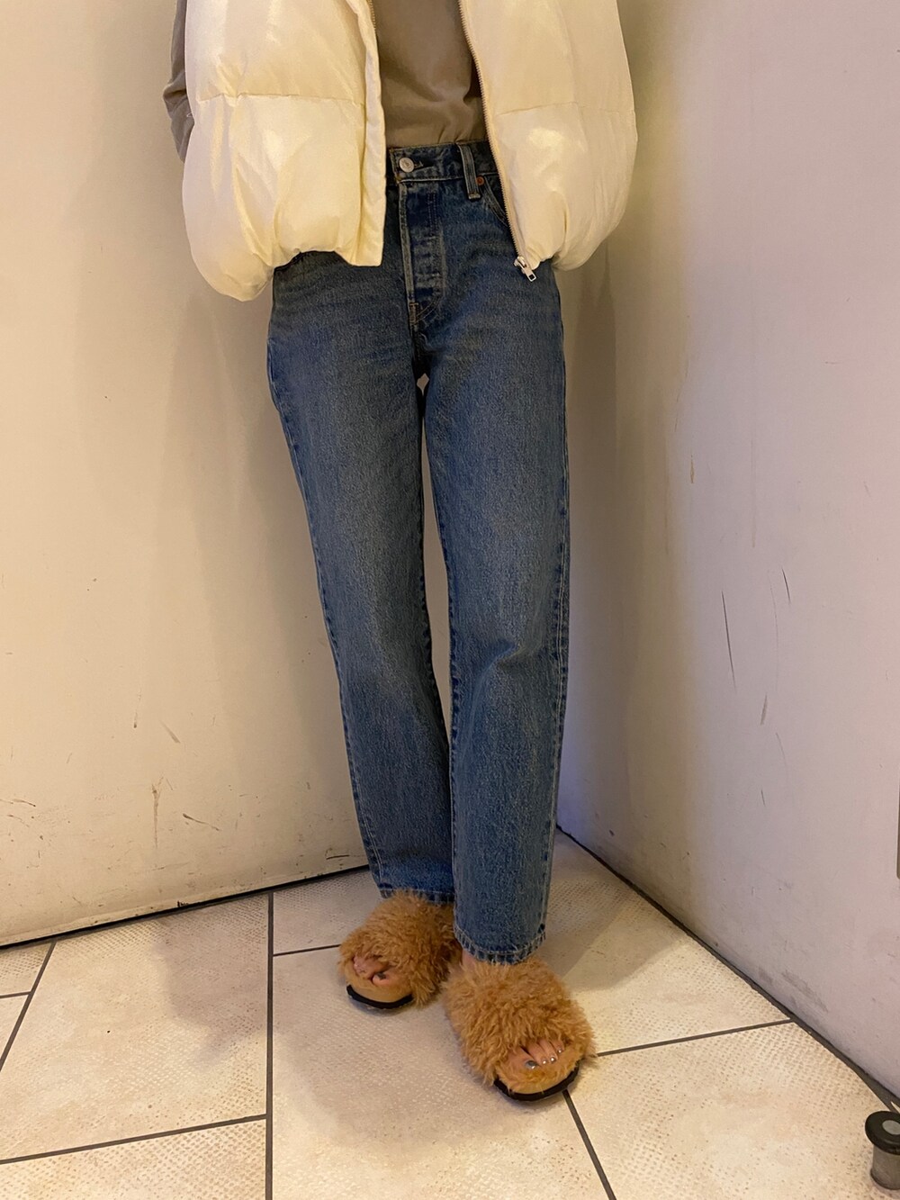 ブルー系のデニムパンツ、グレー系のTシャツ/カットソー、ホワイト系のダウンベストを着用したレディースの秋コーディネートの5枚目の写真