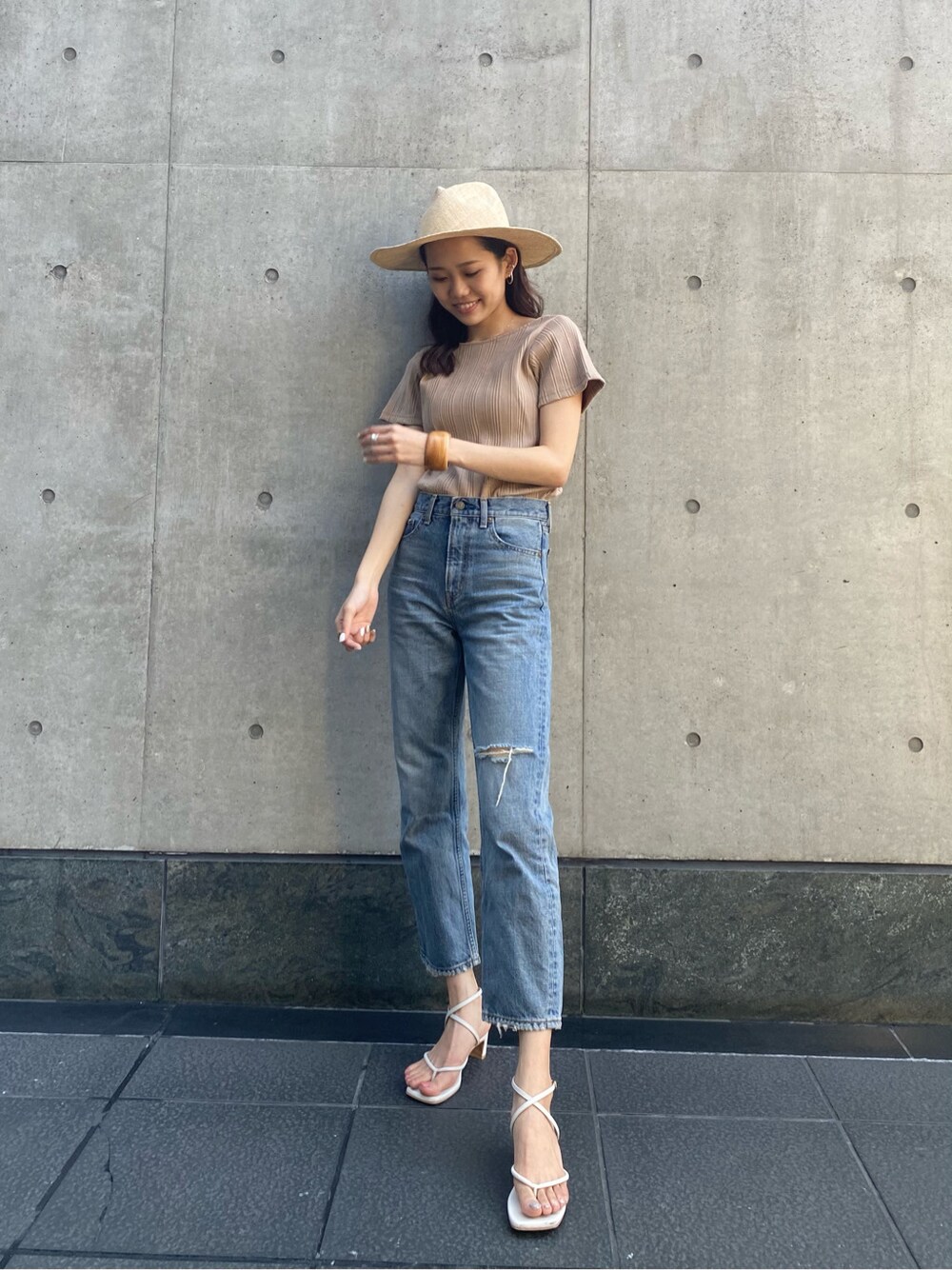 ブルー系のデニムパンツ、ベージュ系のTシャツ/カットソー、ベージュ系のハットを着用したレディースの春コーディネートの2枚目の写真