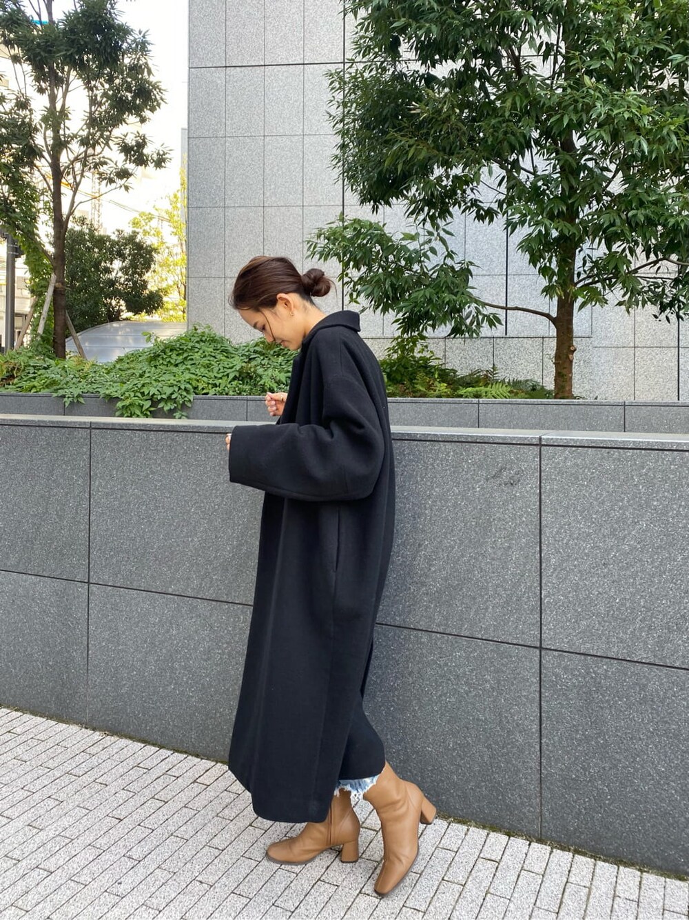 ブラック系のチェスターコート、ブルー系のデニムパンツ、グレー系のニット/セーターを着用したレディースの秋コーディネートの3枚目の写真