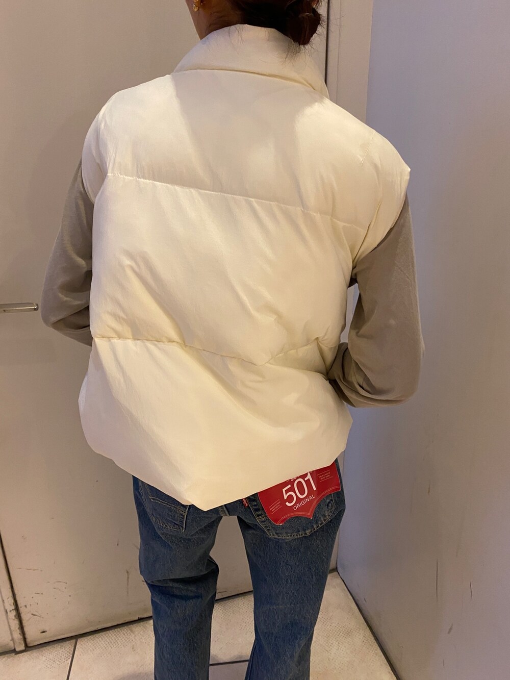 ブルー系のデニムパンツ、グレー系のTシャツ/カットソー、ホワイト系のダウンベストを着用したレディースの秋コーディネートの4枚目の写真