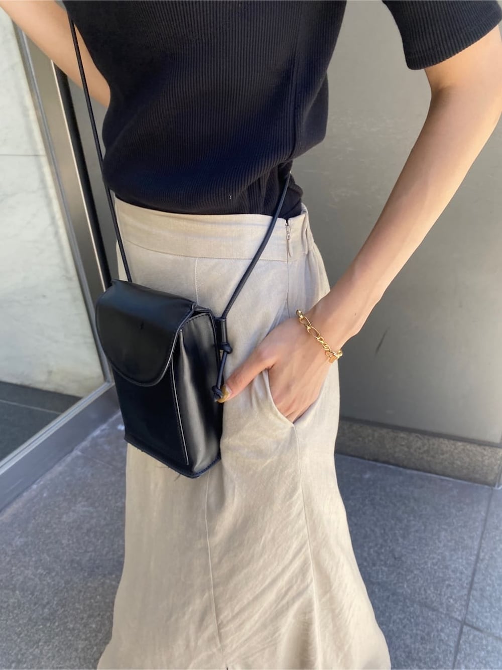 ベージュ系のスカート、ブラック系のTシャツ/カットソーを着用したレディースの夏コーディネートの6枚目の写真