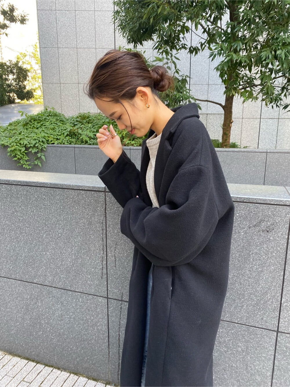 ブラック系のチェスターコート、ブルー系のデニムパンツ、グレー系のニット/セーターを着用したレディースの秋コーディネートの4枚目の写真