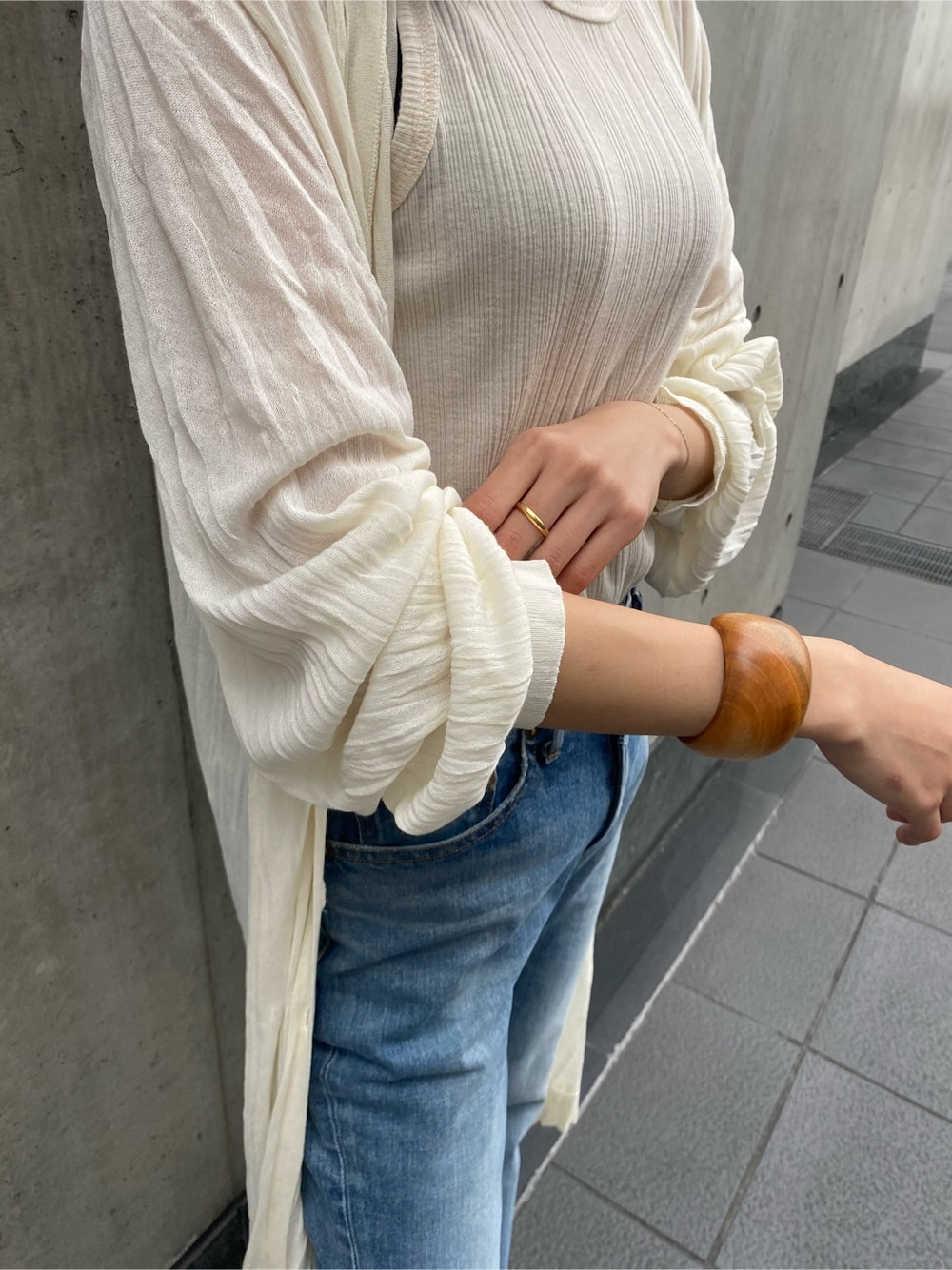 ホワイト系のタンクトップ、ブルー系のデニムパンツ、ホワイト系のカーディガン/ボレロを着用したレディースの春コーディネートの4枚目の写真