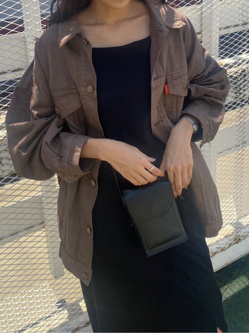 ブラウン系のデニムジャケット、ブラック系のスカート、ブラック系のキャミソールを着用したレディースの夏コーディネートの4枚目の写真