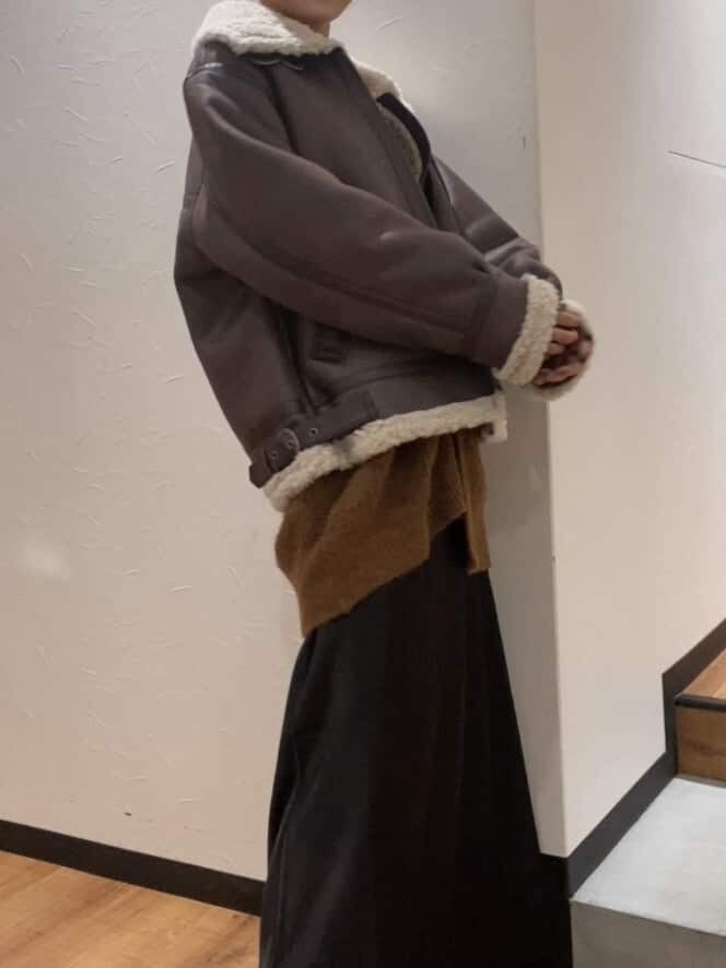 ブラック系のスカート、ブラウン系のムートンコート、ブラウン系のカーディガン/ボレロを着用したレディースの秋コーディネートの2枚目の写真
