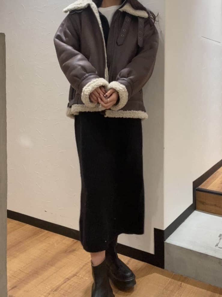 ブラック系のワンピース、ブラウン系のムートンコート、ホワイト系のTシャツ/カットソーを着用したレディースの秋コーディネートの3枚目の写真