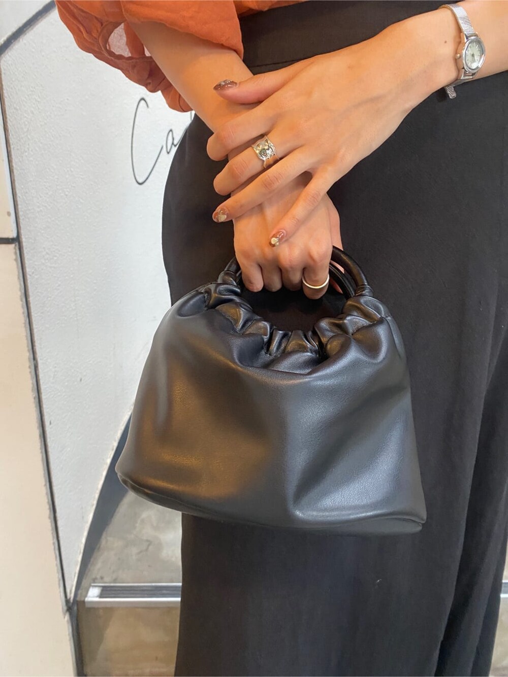 ブラック系のサンダル、オレンジ系のシャツ/ブラウス、ブラック系のスカートを着用したレディースの夏コーディネートの6枚目の写真